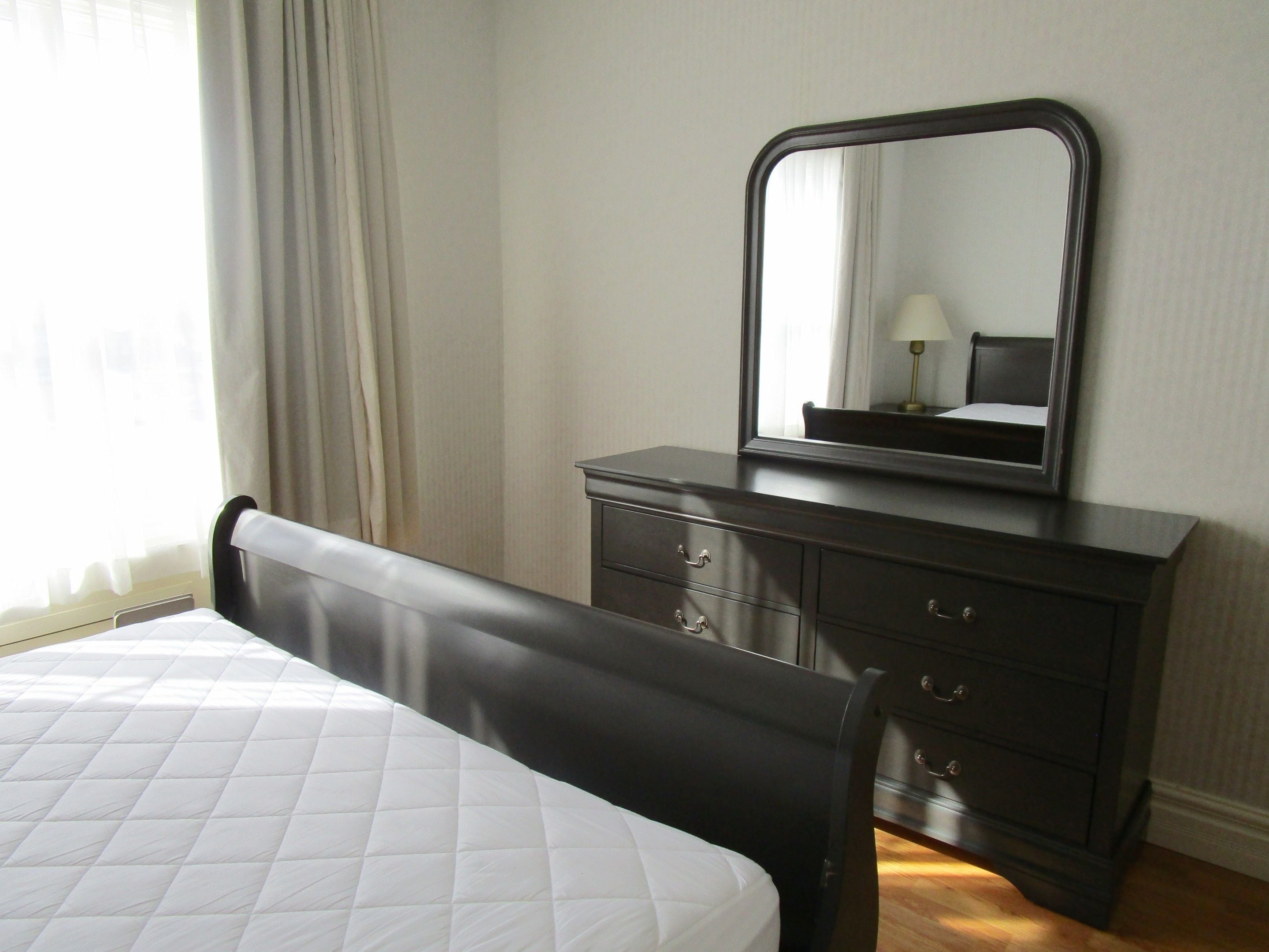 Un dormitorio con una cama, un aparador y un espejo.
