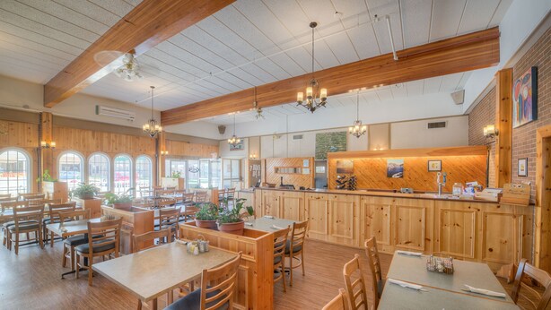 Un restaurant spacieux avec un décor intérieur en bois, de nombreuses tables et un comptoir.