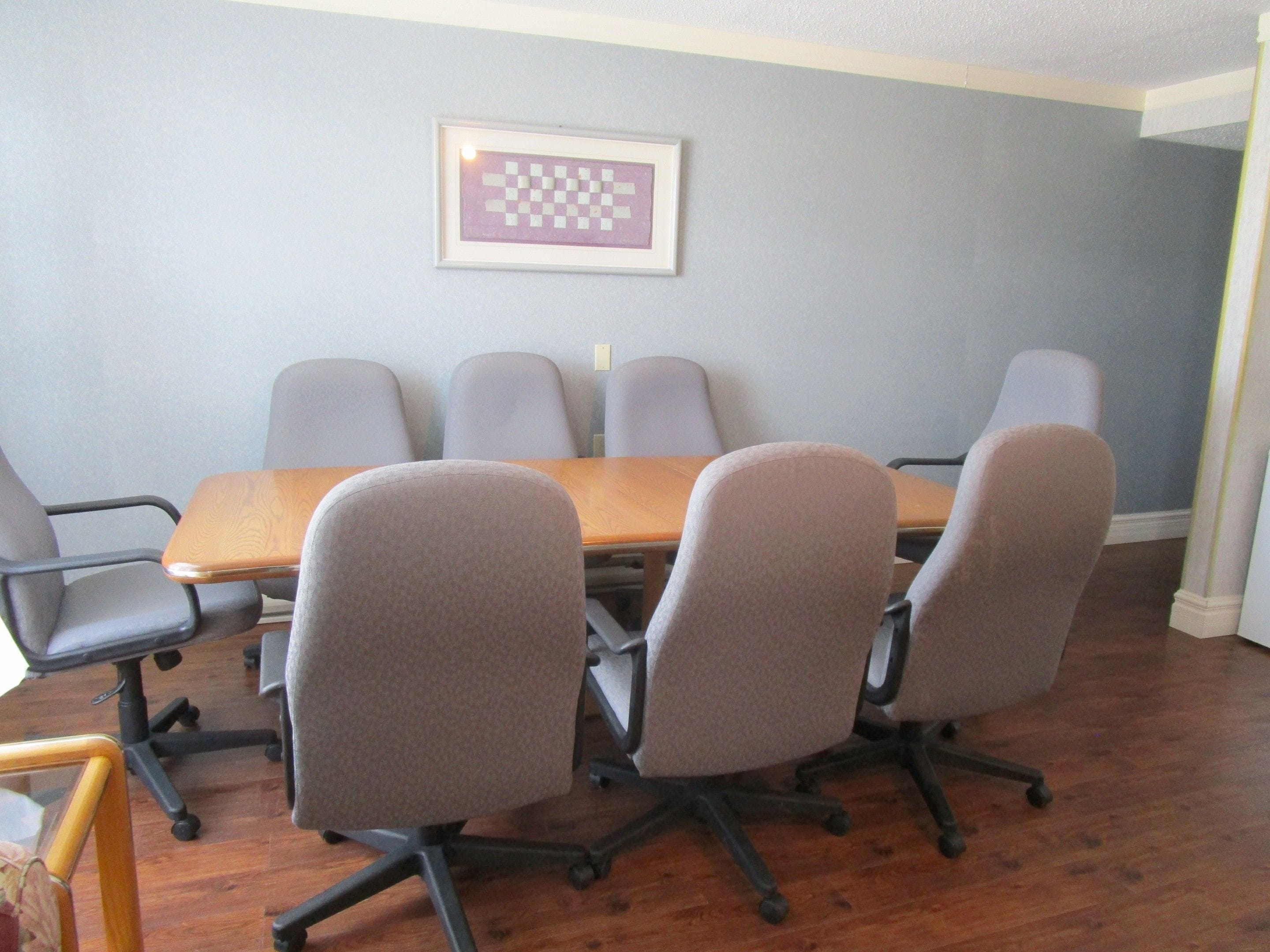 Una sala de conferències amb una taula de fusta i sis cadires de color gris.