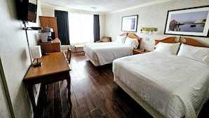 Une chambre d’hôtel avec deux lits, un bureau, une chaise, une télévision et une fenêtre avec des rideaux.