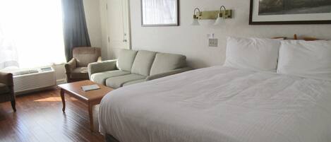 Una habitación de hotel con una cama grande, un sofá, una silla, una mesa y un cuadro en la pared.