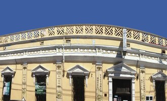 A building with a classical architectural style, featuring columns and a balcony with intricate lattice work.