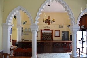 A reception area with a check-in counter, a chandelier, and traditional architectural arches.