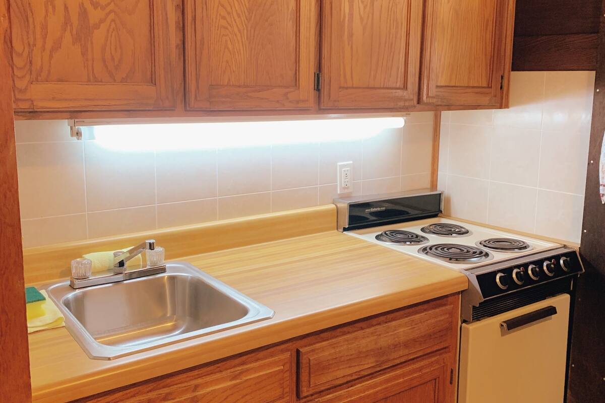 A kitchen with wooden cabinets, a stainless steel sink, a stove, and a built-in oven.