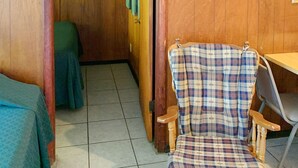 Una habitación de madera con una silla de cuadros, una puerta de madera y una mesa.