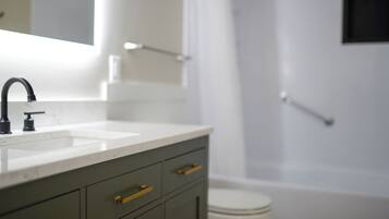 Et moderne badeværelse med en hvid vask, en mørkegrøn kommode og et hvidt toilet.
