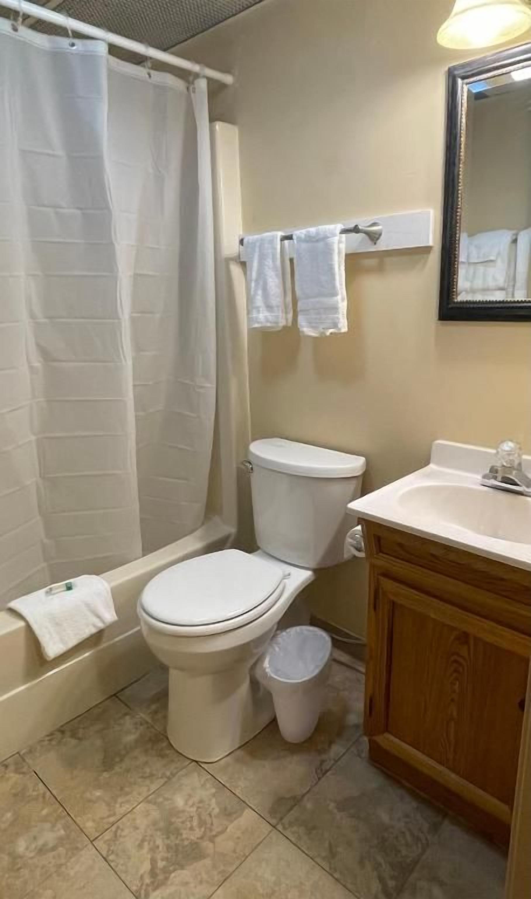 Une salle de bain équipée d’une baignoire, de toilettes, d’un lavabo et d’un miroir.