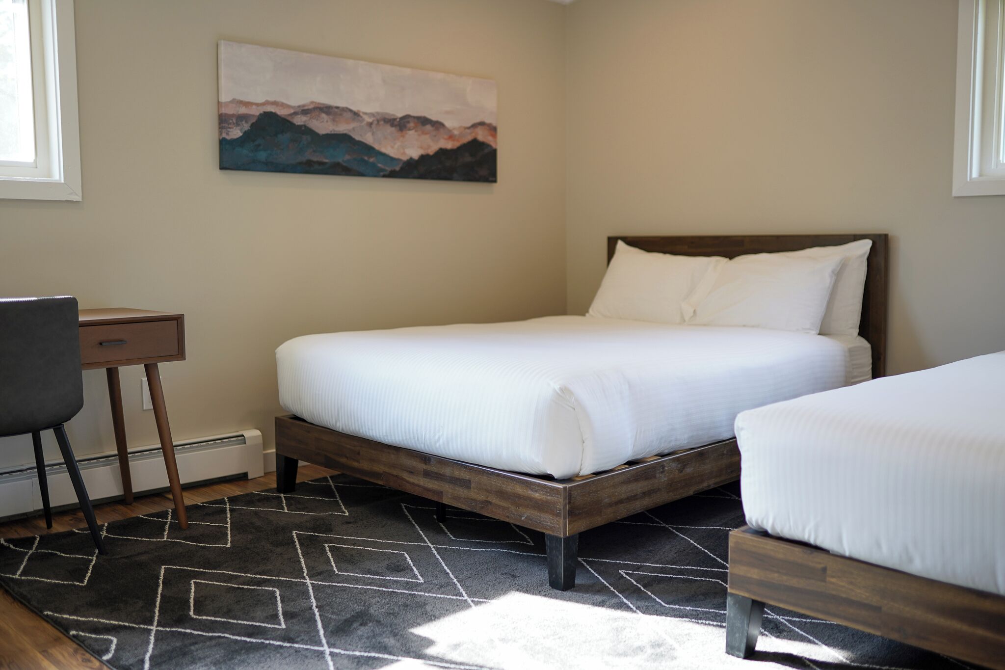 A bedroom with a bed, a desk, and a painting on the wall.