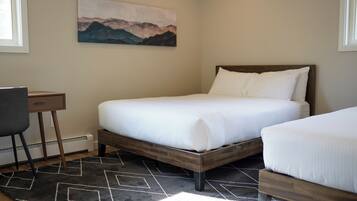 A bedroom with a bed, a desk, and a painting on the wall.