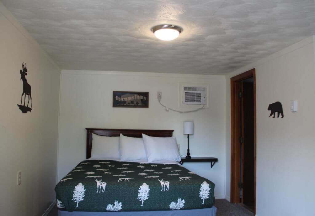 A bedroom with a bed, a wall-mounted air conditioner, and a door with a bear silhouette.
