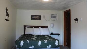 A bedroom with a bed, a wall-mounted air conditioner, and a door with a bear silhouette.