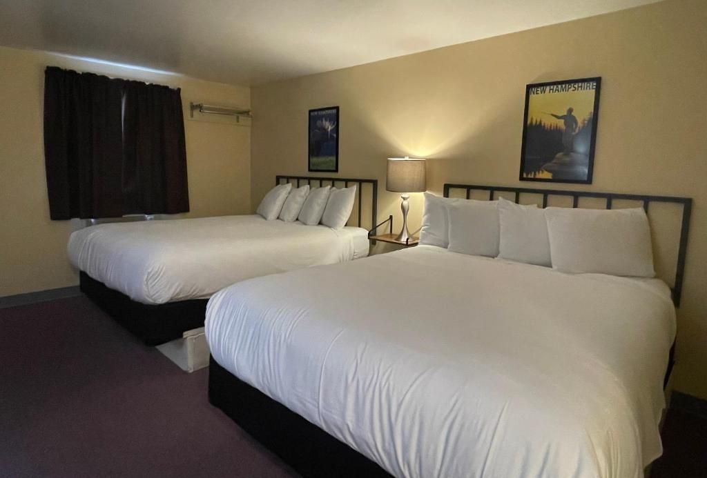 Una habitación de hotel con dos camas, una mesita de noche con lámpara y dos carteles en la pared.