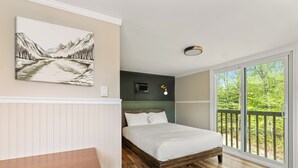Et soveværelse med en træseng, et natbord, et ophængt billede, et vindue med udsigt til grøn vegetation, og en loftlampe.