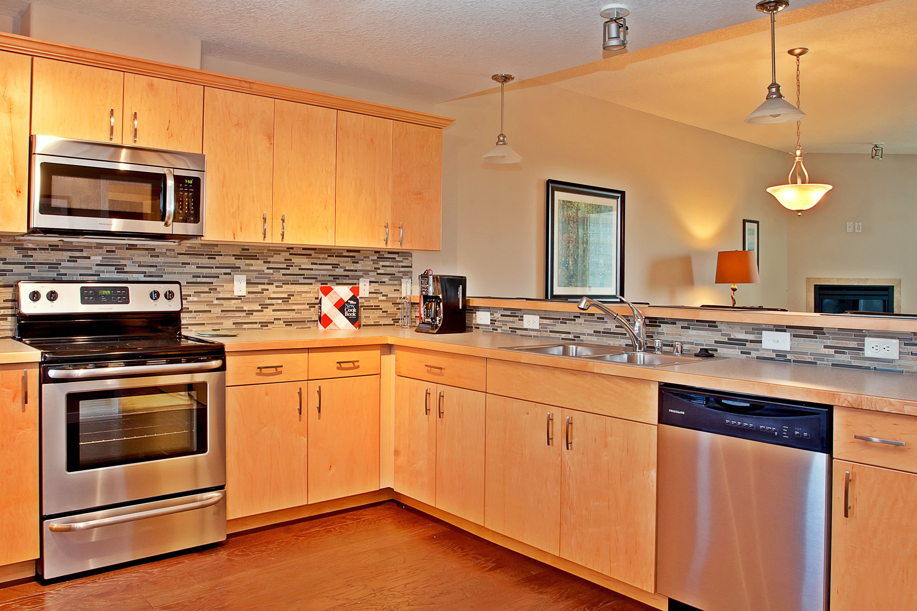A modern kitchen with stainless steel appliances, wooden cabinets, and a tiled backsplash.