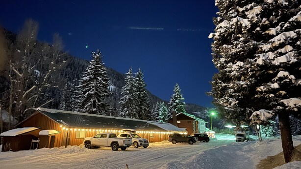 A snow-covered landscape with a building featuring a wooden exterior and a sloped roof. - Wolf Creek Ranch Ski Lodge (South Fork)