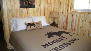 Ein Zimmer mit Holzwänden und einem Bett mit einem Elch-Motiv und dem Text "Moose Crossing".