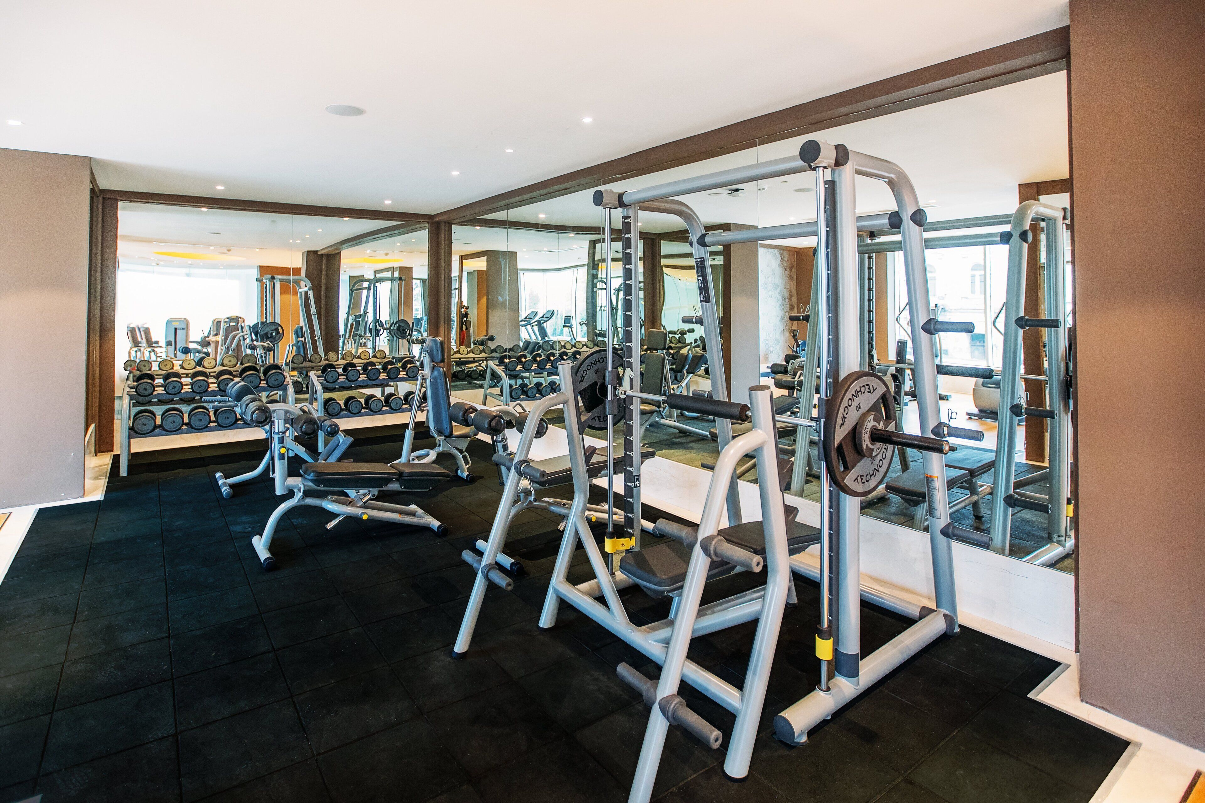 A gym with weightlifting equipment, treadmills, and dumbbells.