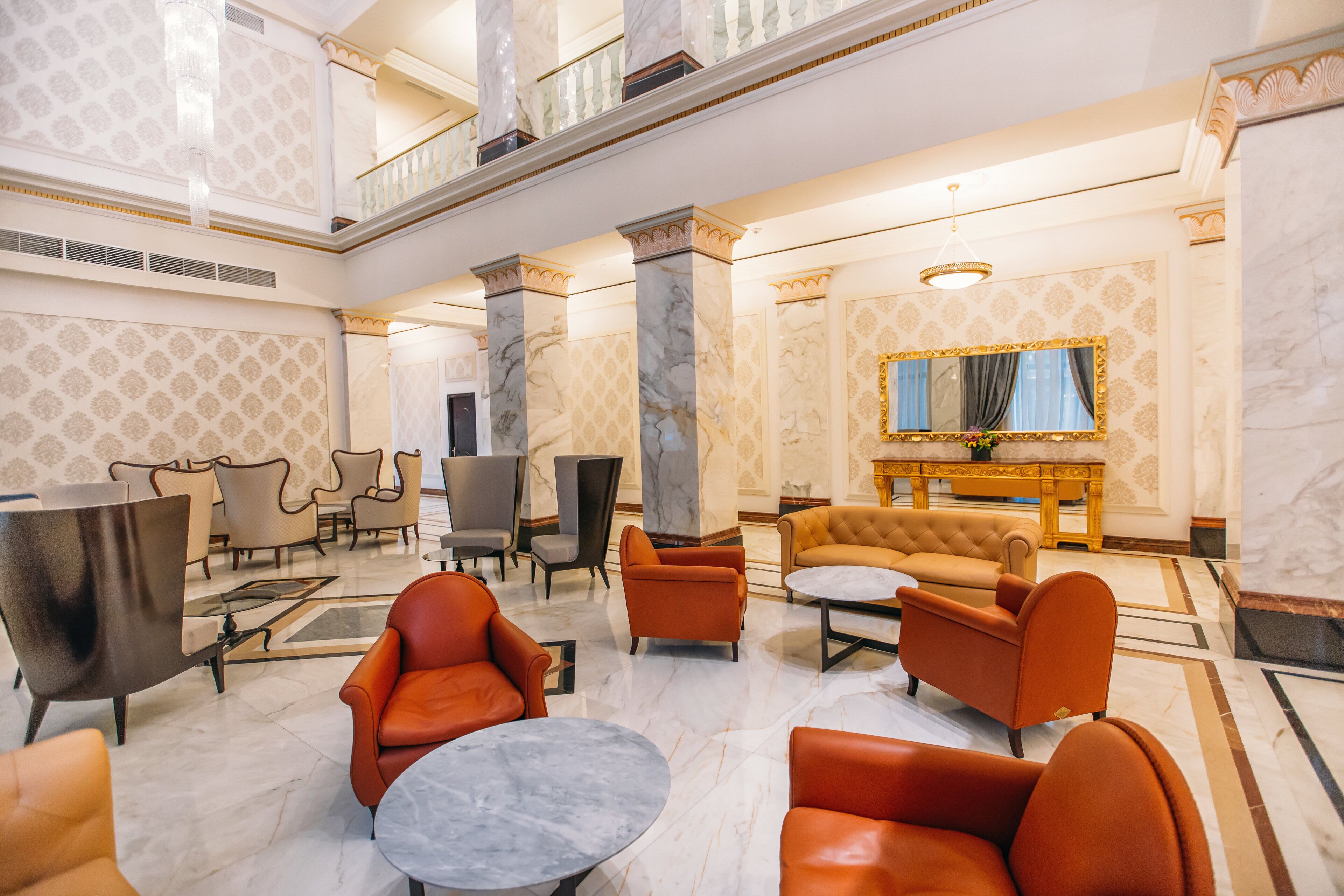 Eine geräumige Lobby mit hoher Decke, Marmorböden und verschiedenen Sitzmöglichkeiten, darunter Ledersessel und -sofas.