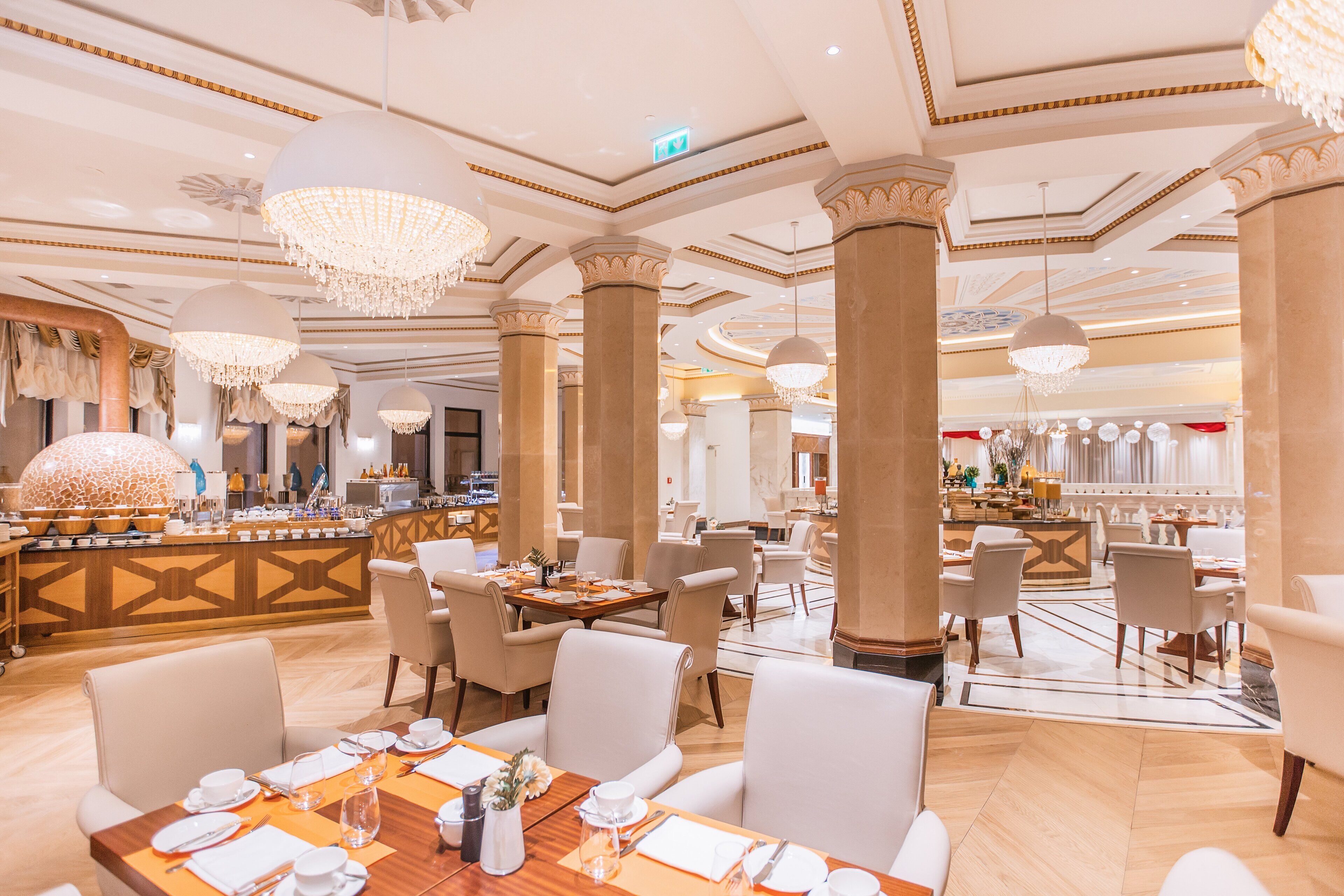 Un comedor de hotel espacioso con techos altos, candelabros y una barra central.