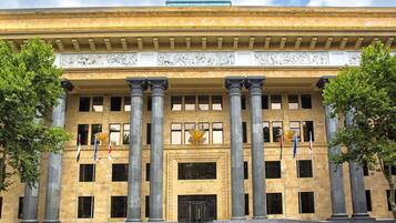 A large building with classical architecture, featuring tall columns, a central entrance, and multiple flags.
