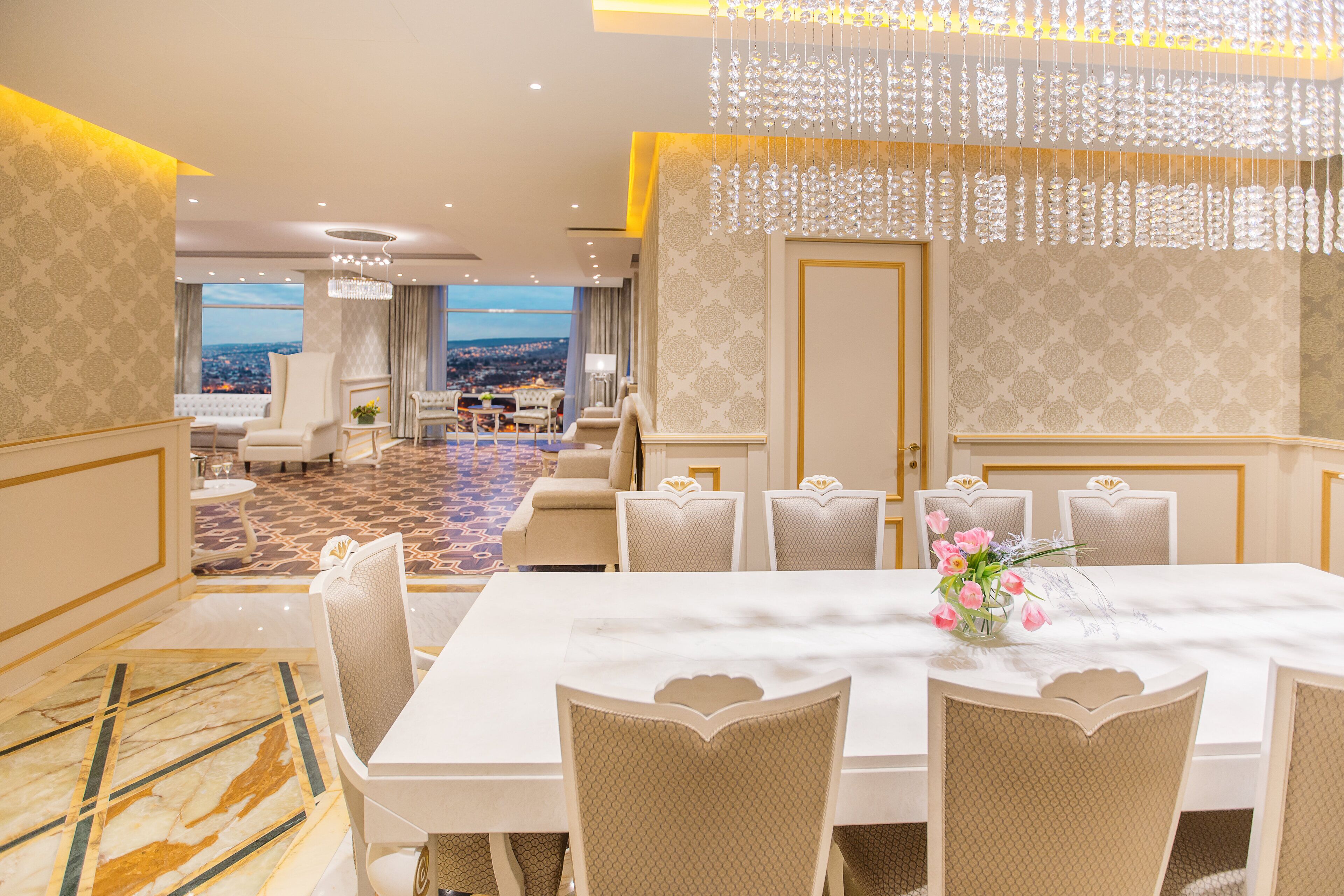 A spacious dining area with a marble floor, a large table, and six chairs.