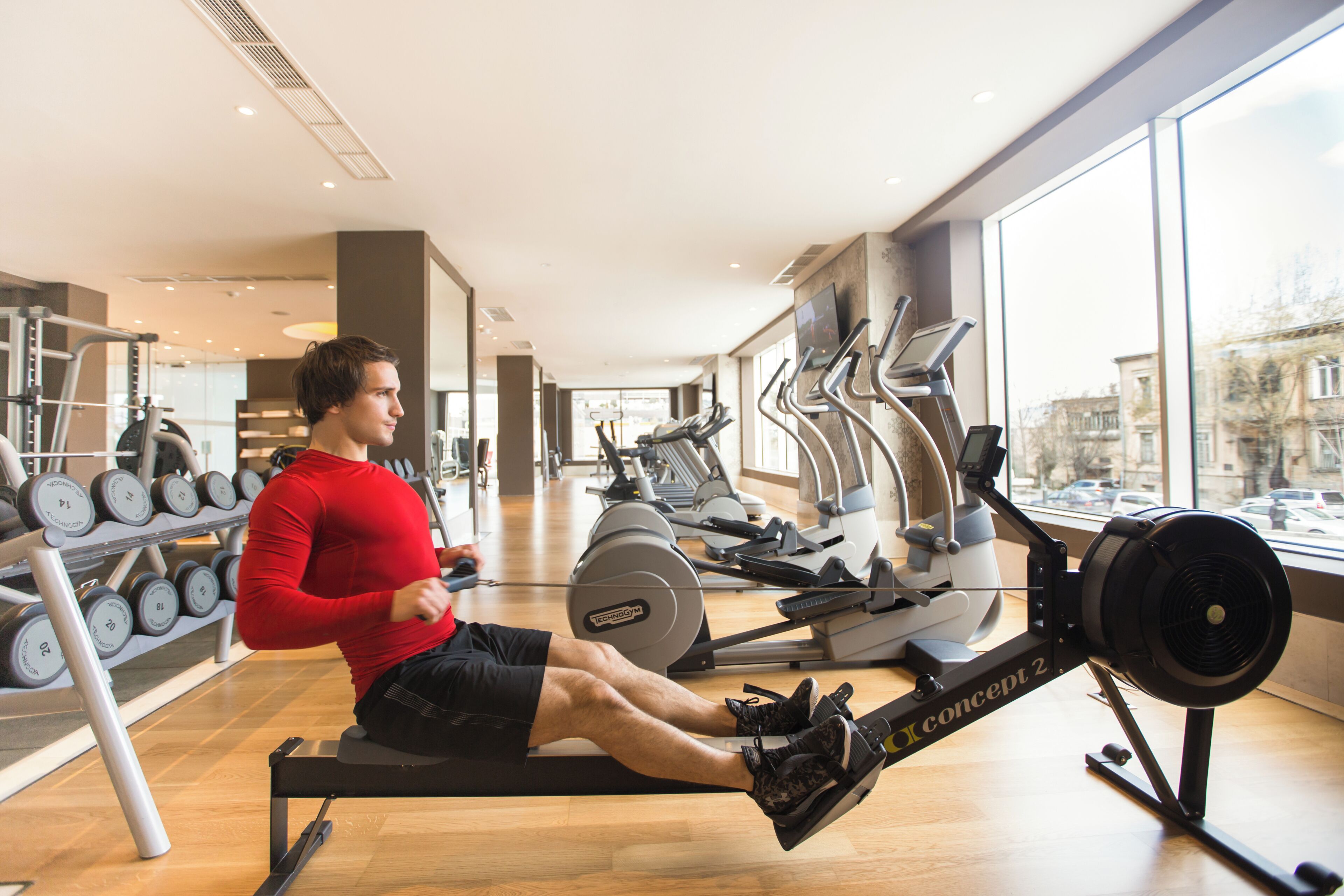 A gym with rowing machines, dumbbells, and cardio equipment.