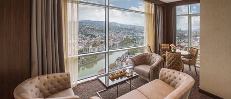 A spacious room with large windows offering a city view, a comfortable seating area, and a small table with decorative items.