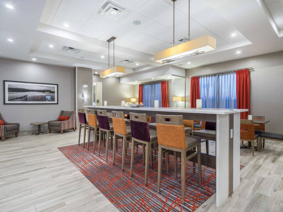 A modern dining area with a long table, multiple chairs, and a patterned rug.