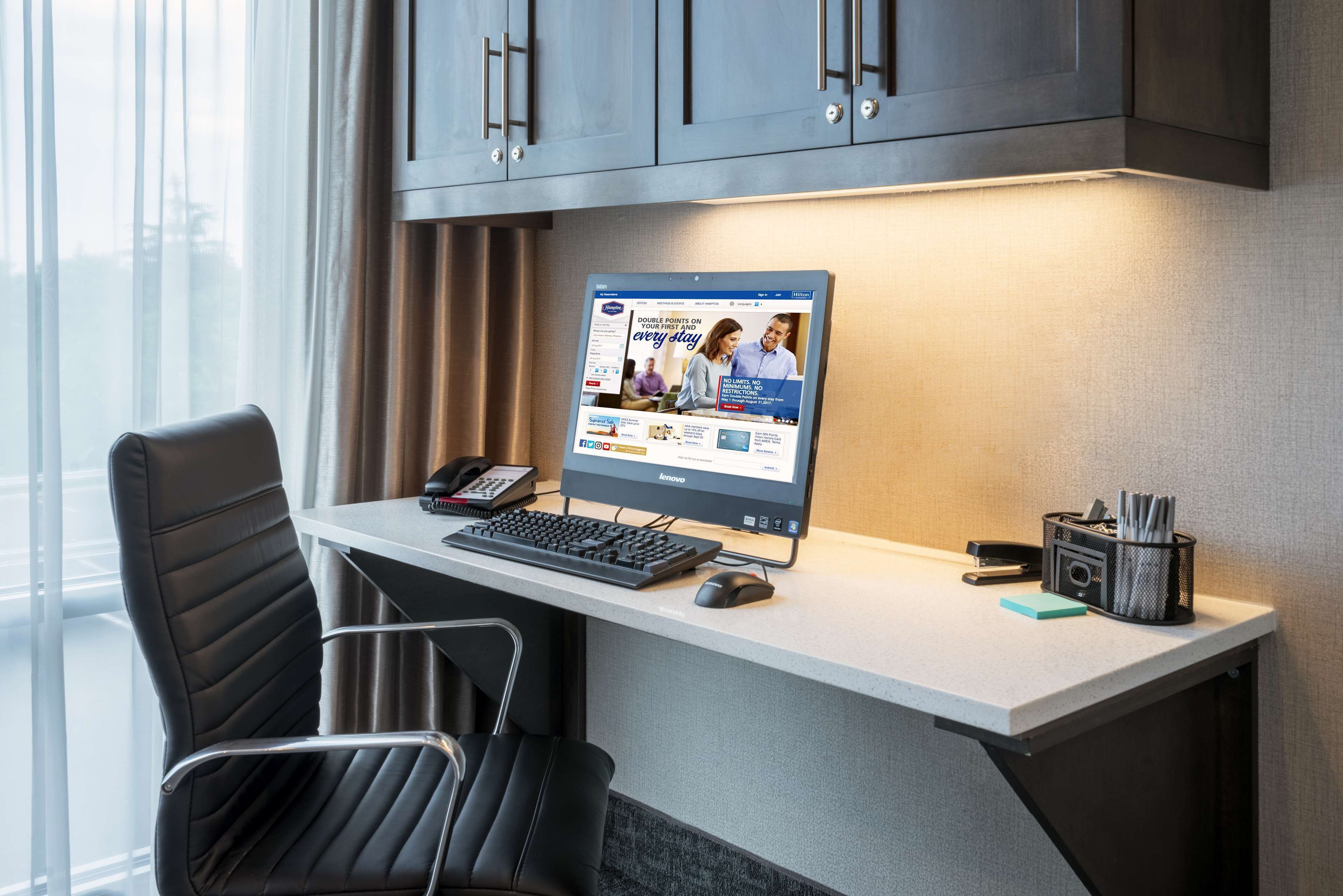 A modern office desk with a desktop computer, a keyboard, a mouse, and a telephone.