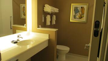 Une salle de bain avec un lavabo blanc, un miroir, des toilettes et un porte-serviettes.