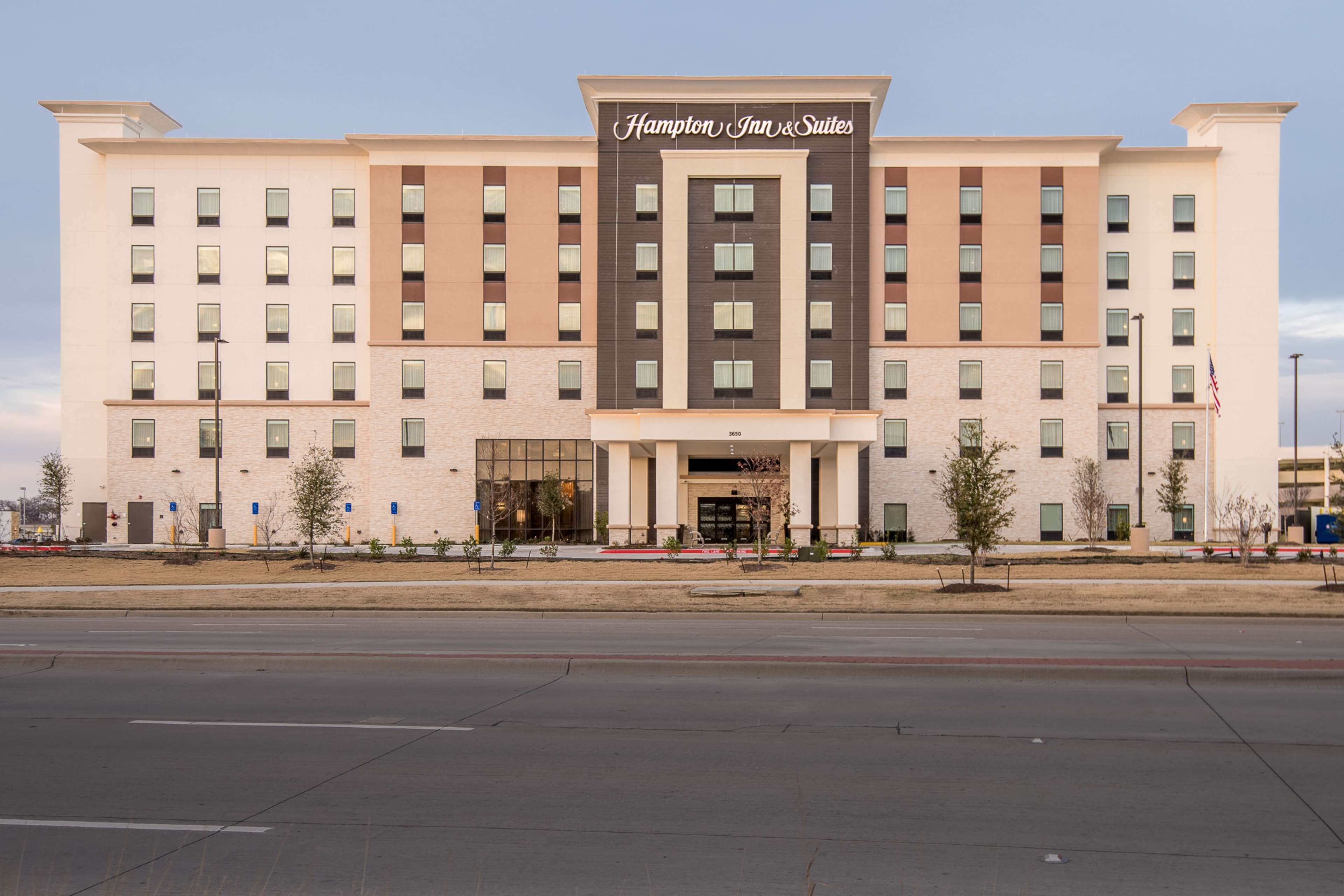 A large, modern hotel building with a prominent sign reading "Hampton Inn & Suites".