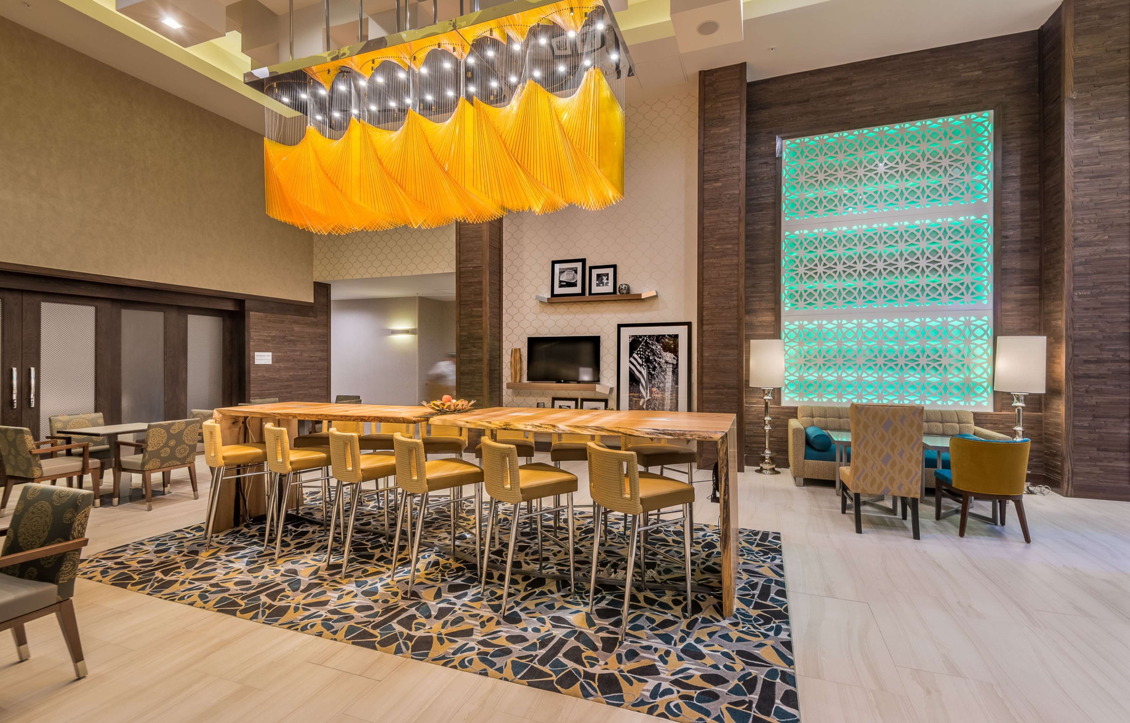 A spacious lobby with a large dining area, a modern chandelier, and a decorative wall panel.