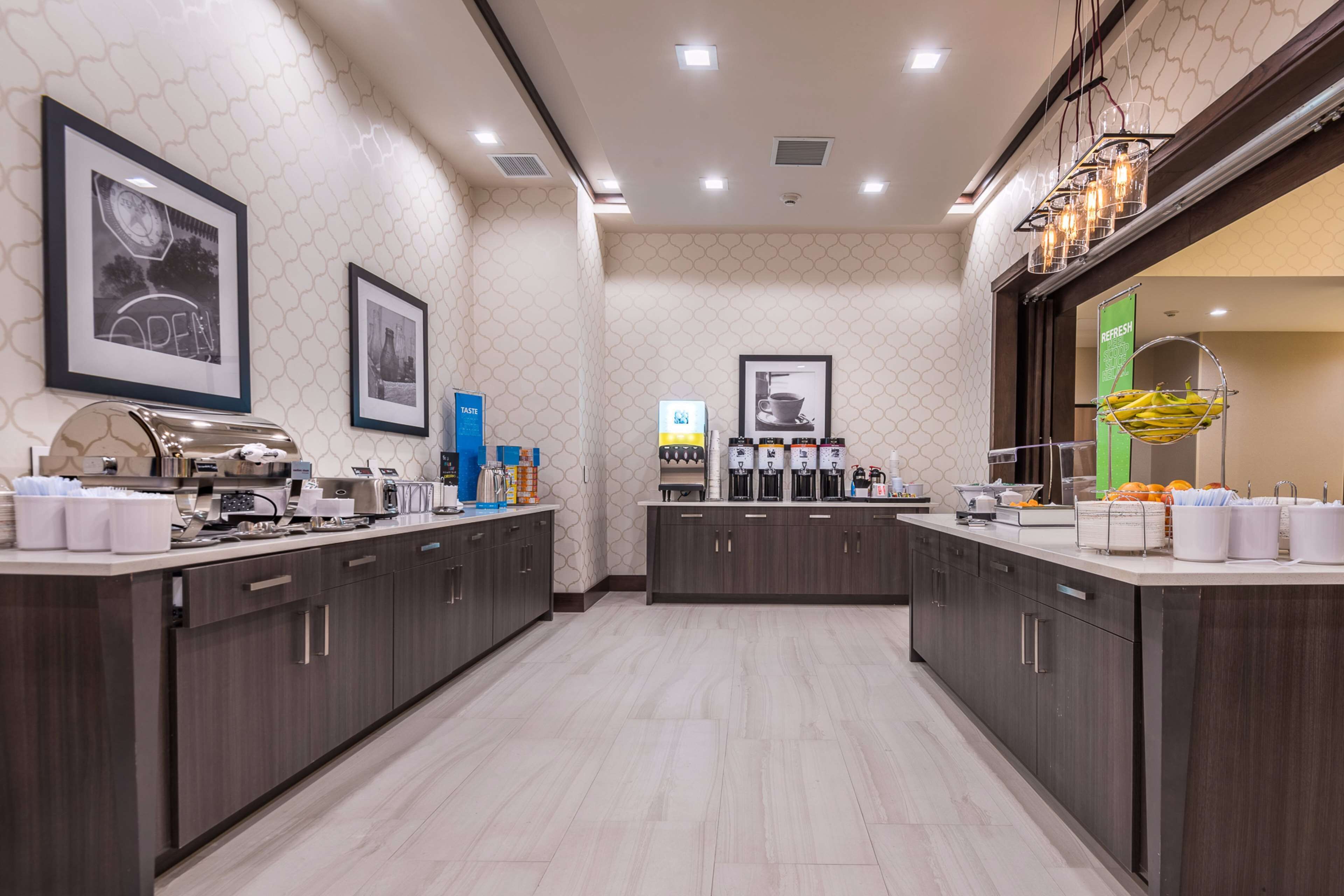 A modern kitchen with dark wood cabinets, a central island, and a coffee station.