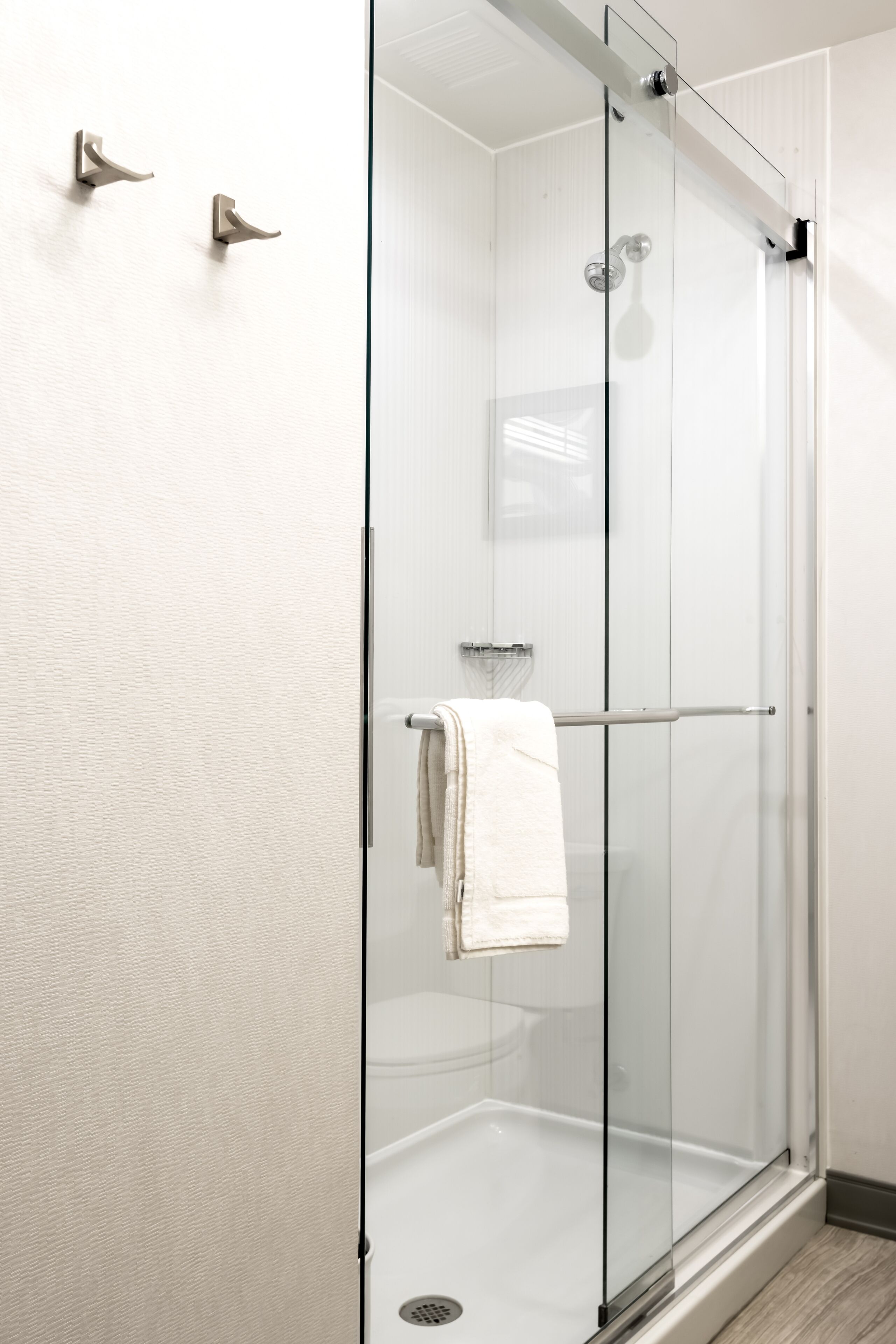 A modern bathroom with a glass-enclosed shower, a towel rack, and a visible toilet.