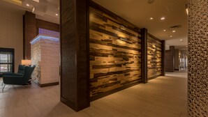 A modern hotel lobby with a wooden wall panel and a seating area with a lamp. - Hampton Inn & Suites Dallas-The Colony, TX (The Colony)