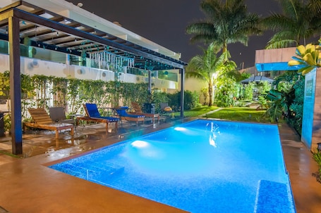 Una piscina al aire libre, sombrillas, sillones reclinables de piscina