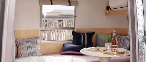 A cozy interior with a bench, pillows, a small table, and a bottle.
