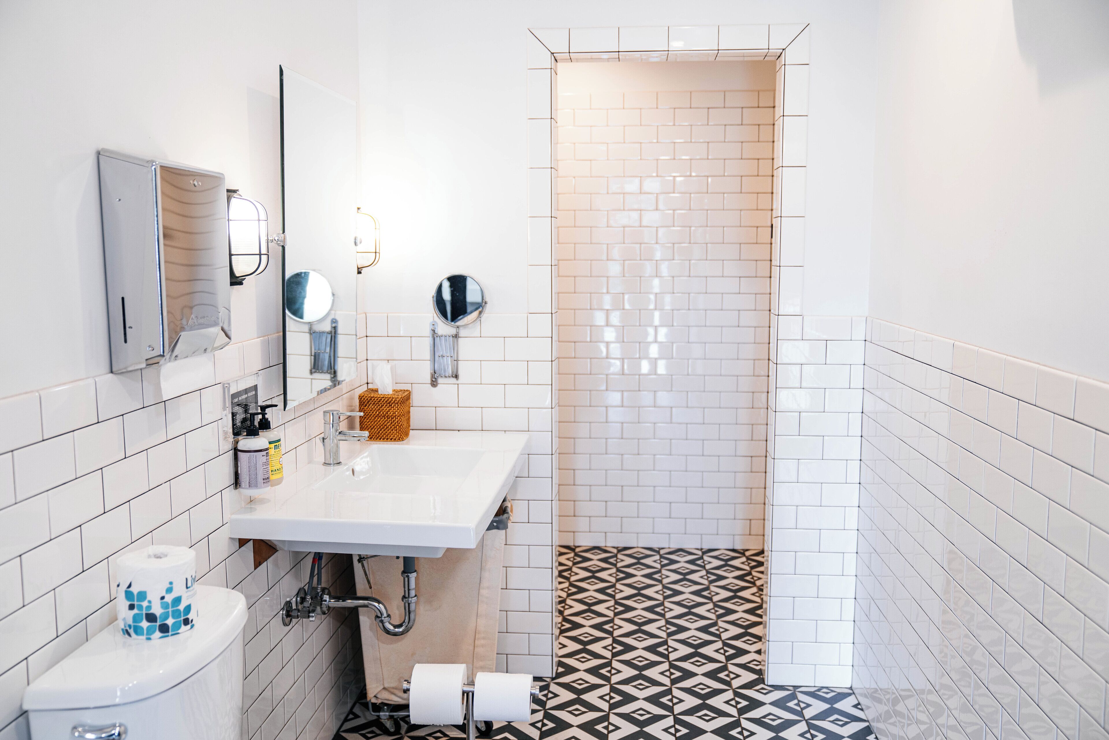 Une salle de bain avec un lavabo blanc, des toilettes et un espace douche agrémenté de carreaux à motifs.