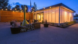 A modern building with a glass facade, a wooden deck, and string lights. - The Amigo Motor Lodge (Salida)