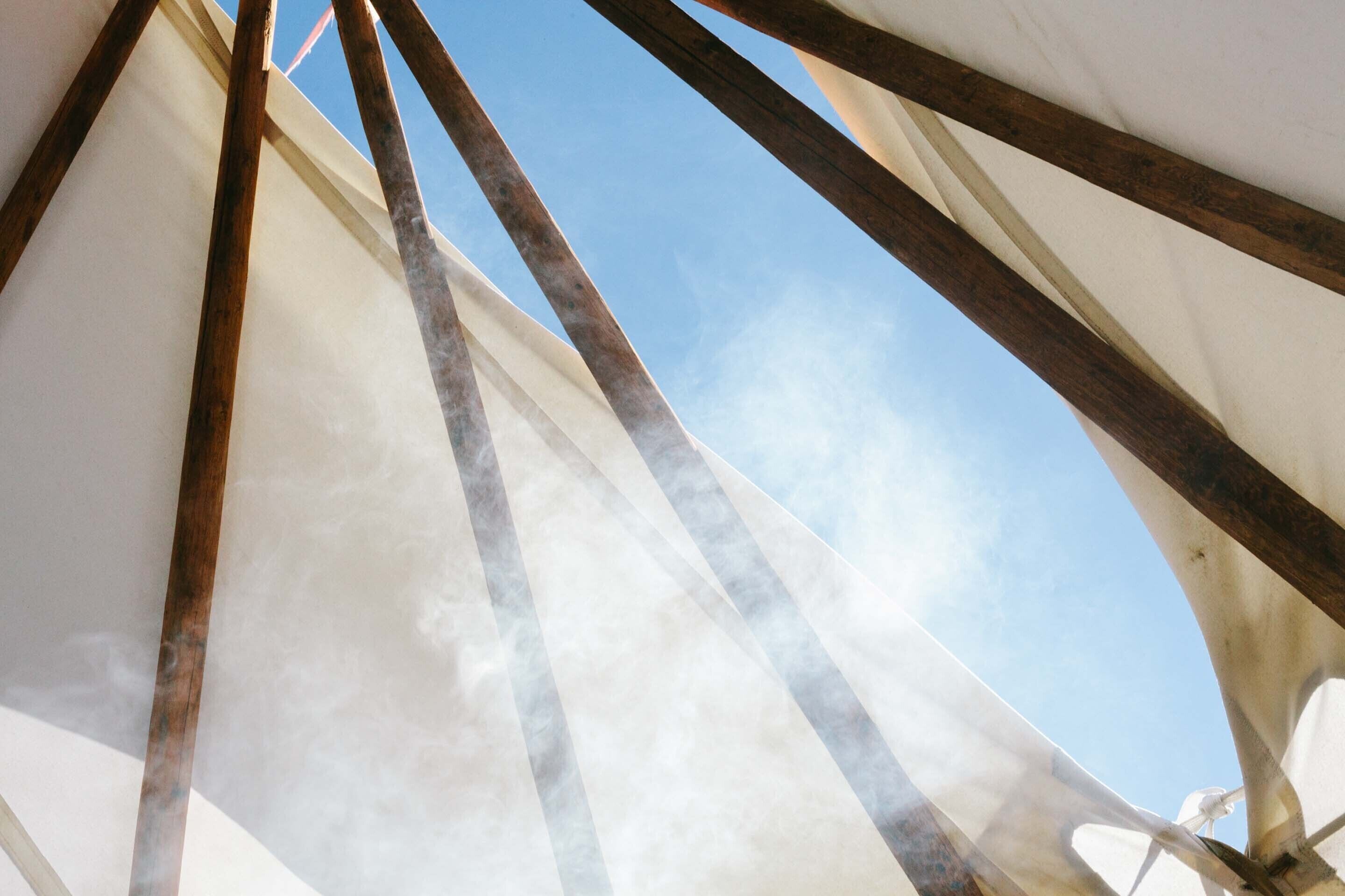 Primer plano del borde de una vela y vigas de madera, con un cielo despejado al fondo.