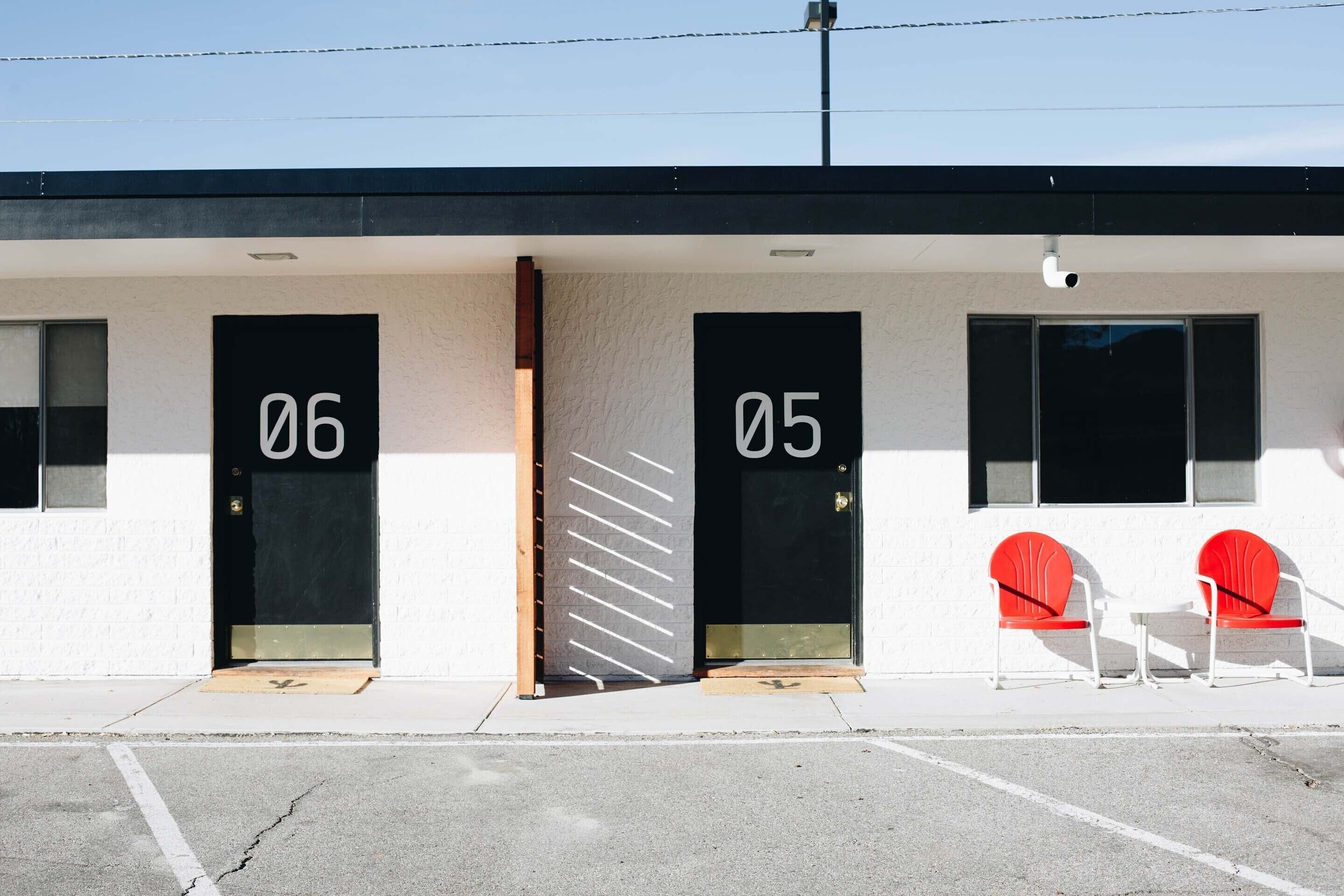 Un edificio con puertas numeradas, 06 y 05, y dos sillas rojas en el exterior.