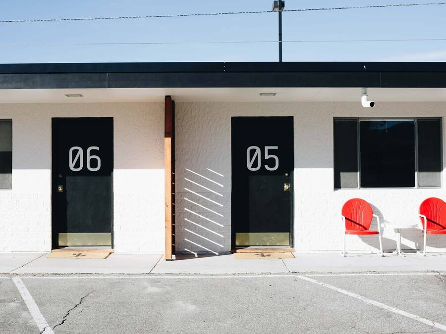 Un edificio con puertas numeradas, 06 y 05, y dos sillas rojas en el exterior.