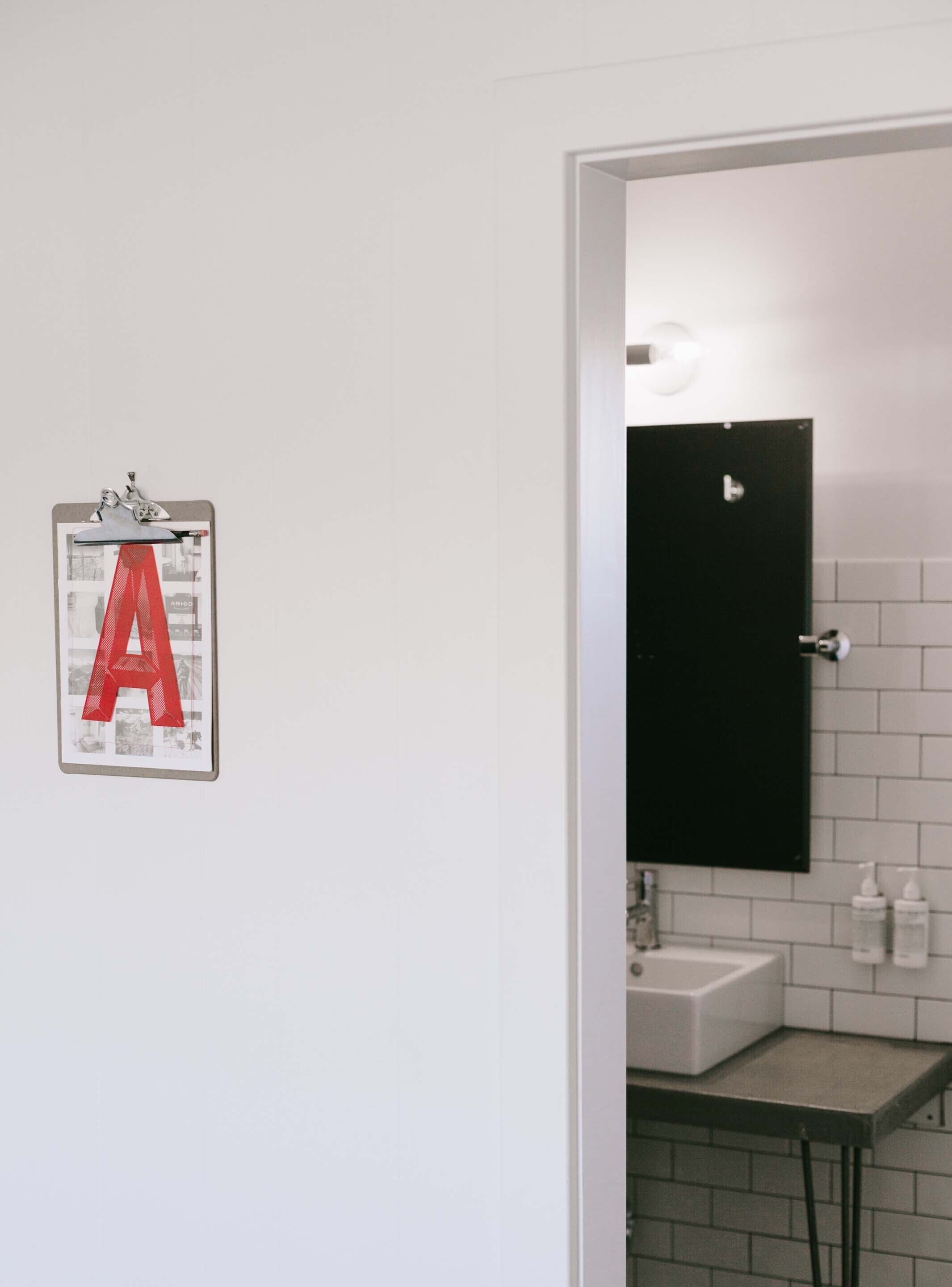 A bathroom with a white sink, a black mirror, and a wall-mounted toilet.