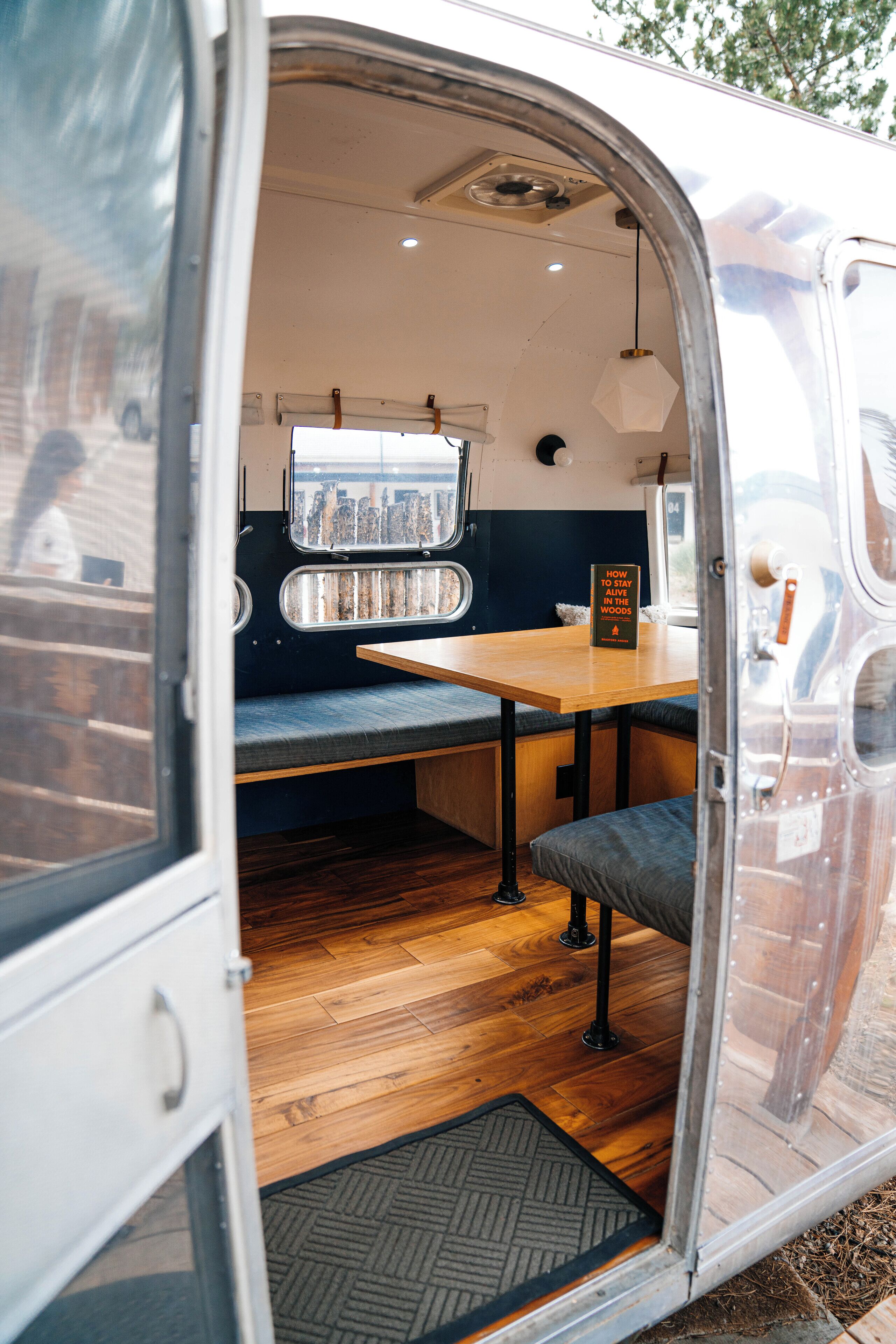 A van interior with a wooden table, bench seating, and a window with city views.