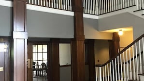 A spacious interior with a central open area, a staircase with wooden balusters, and a high ceiling. - Dunes Express Inn & Suites (Hart)