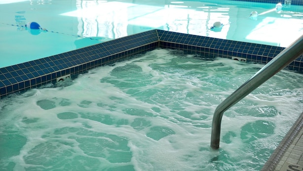 A hot tub with a tiled edge and a metal ladder. - Dunes Express Inn & Suites (Hart)
