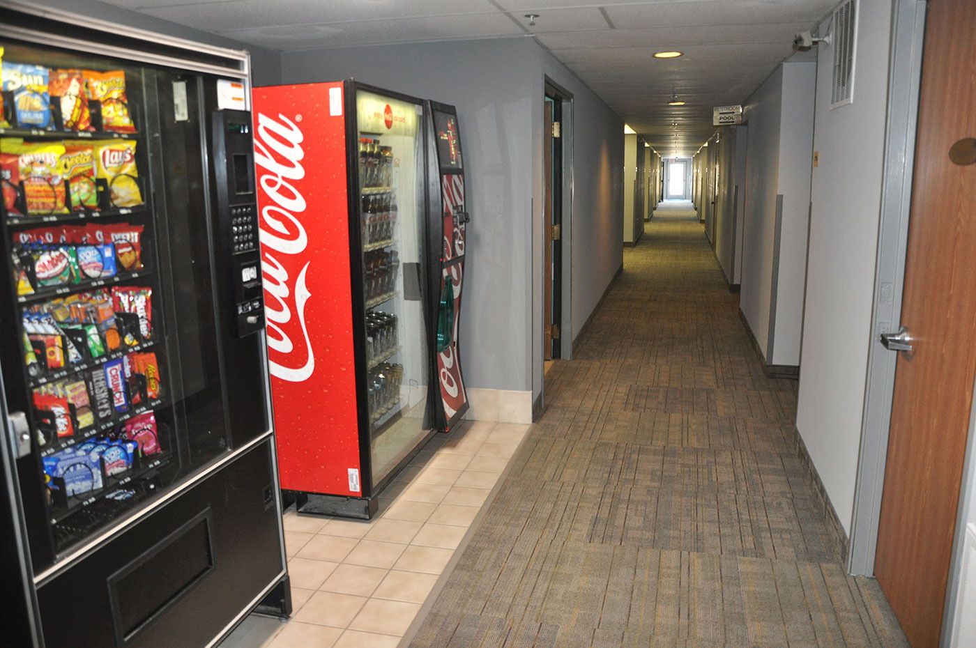 Un pasillo con máquinas expendedoras a la izquierda, que ofrecen aperitivos y Coca-Cola.