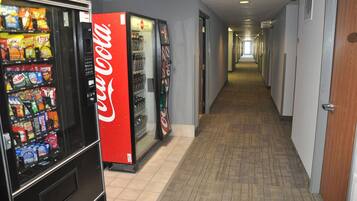 Un pasillo con máquinas expendedoras a la izquierda, que ofrecen aperitivos y Coca-Cola.