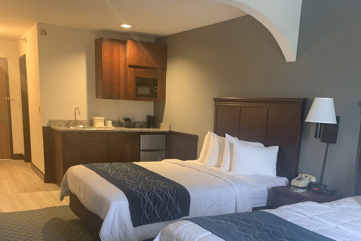 Une chambre d’hôtel avec deux lits, une kitchenette et une salle de bain.