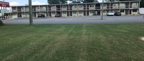 Un motel con varias habitaciones, un estacionamiento y un área verde al frente.